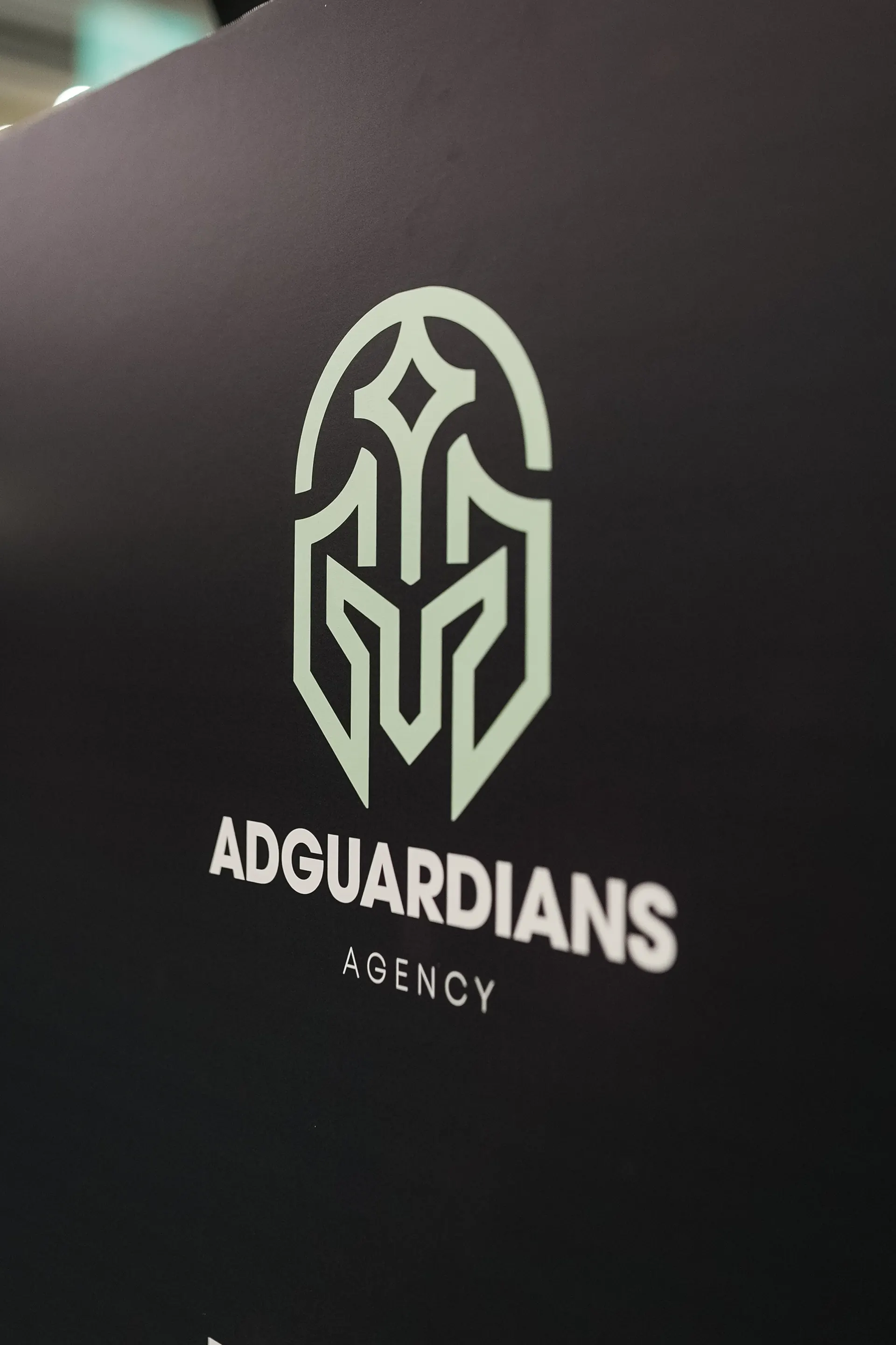 The AdGuardians Agency logo on a black wall